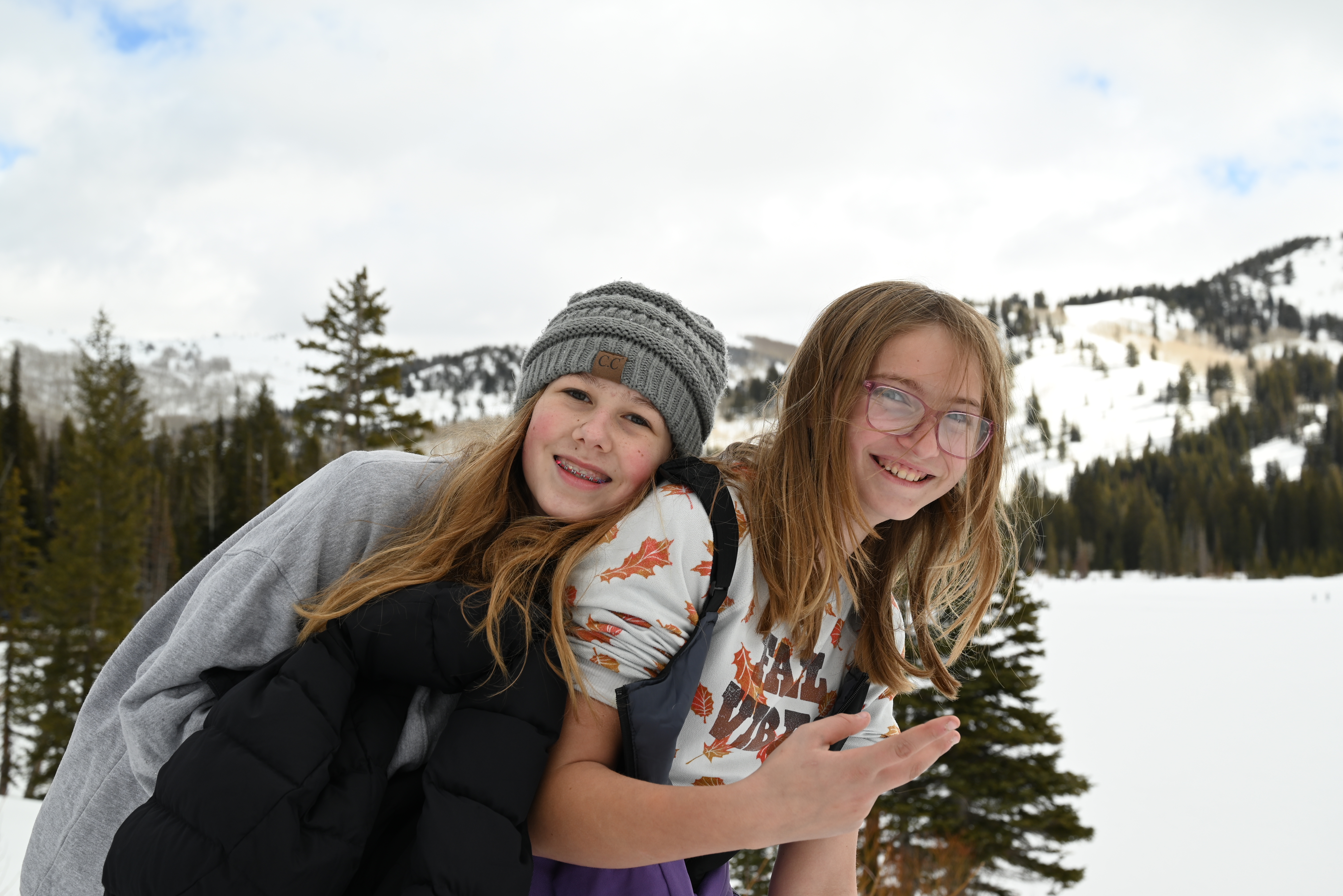 Two girls pose together with a snow-covered mountain backdrop at Solitude Nordic Center