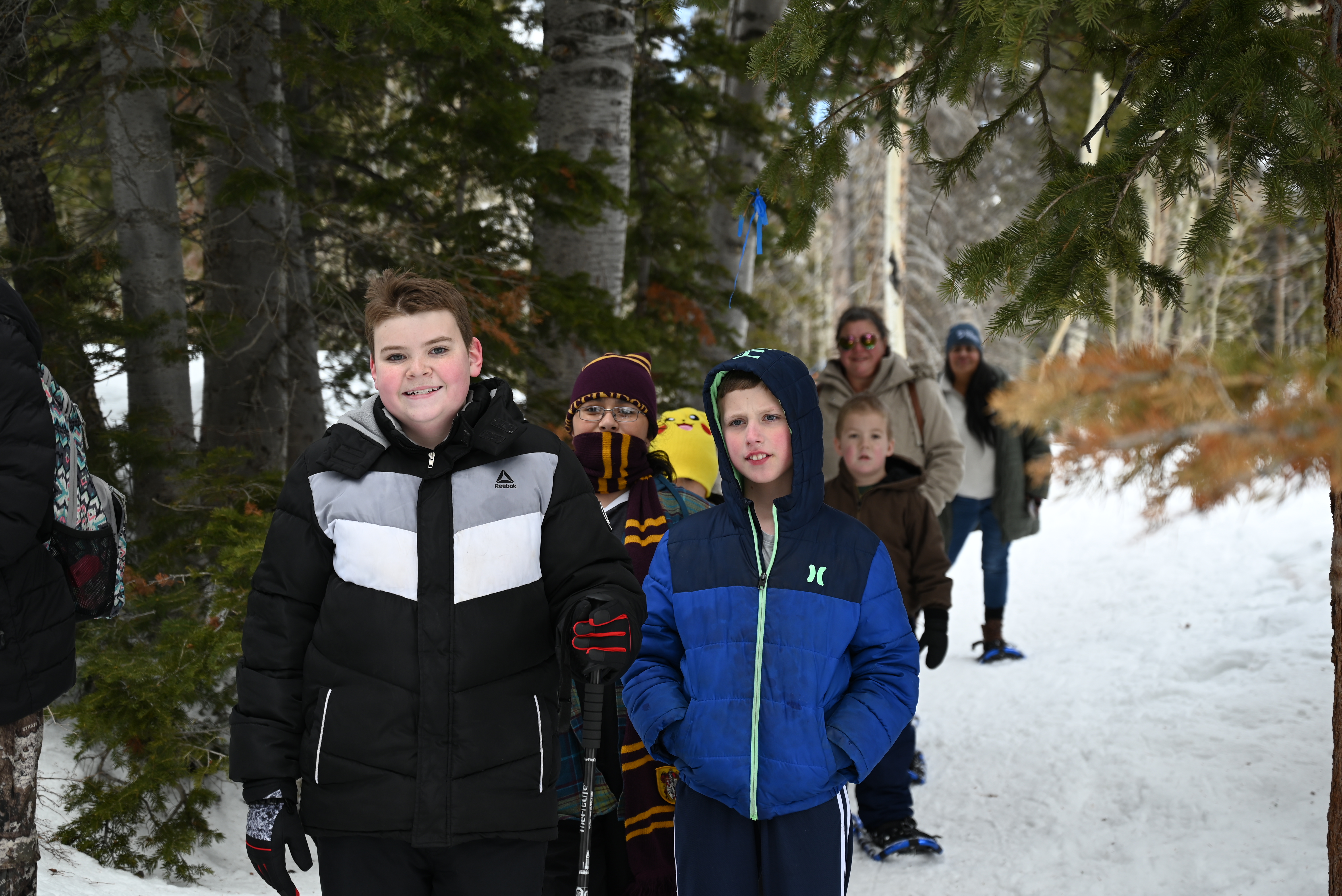 A group of students hiking together through a snowy forest trail on snowshoes