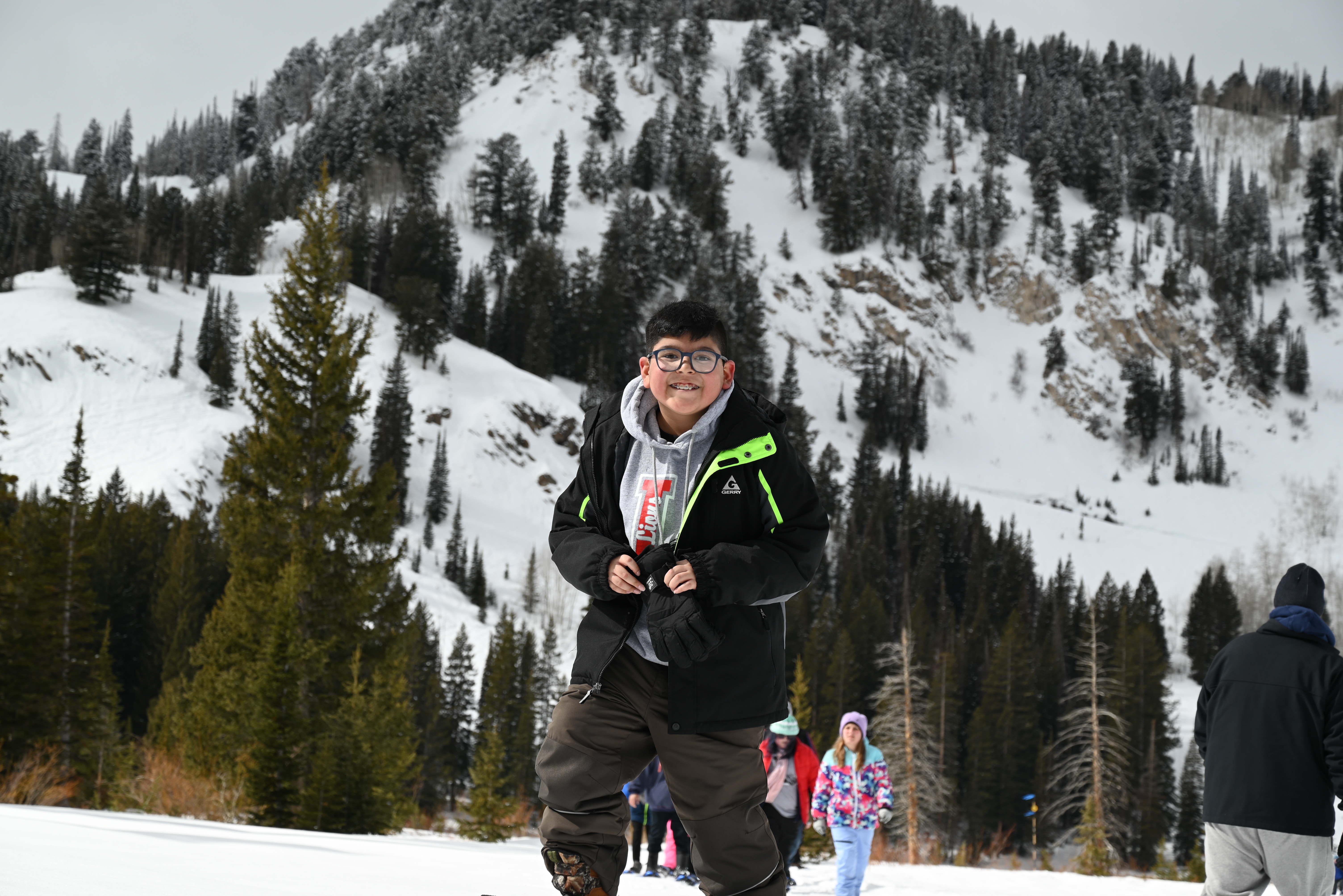 A boy smiling on a snowy slope with a mountain view behind him